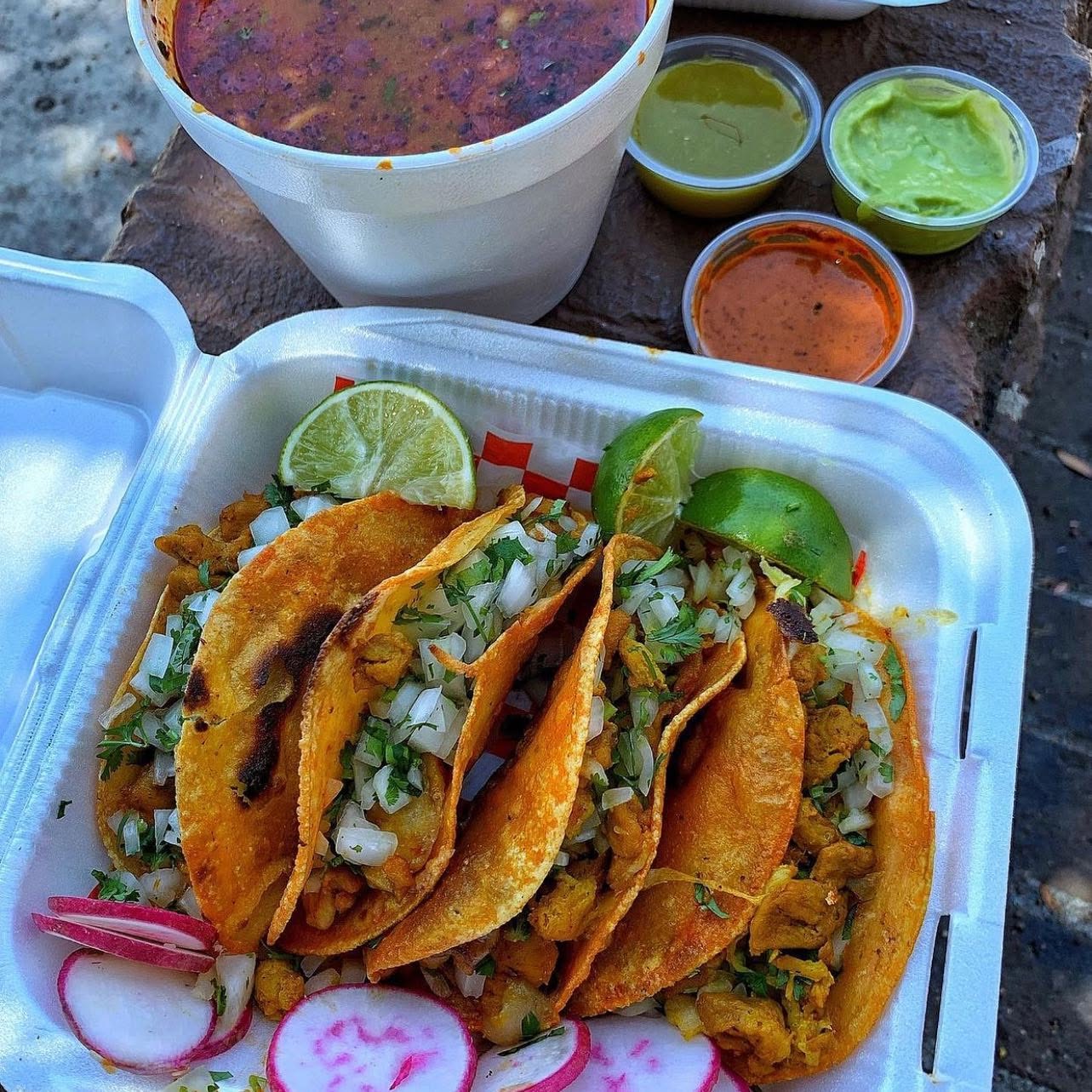 A tray of street tacos with lime, radish, and house salsas