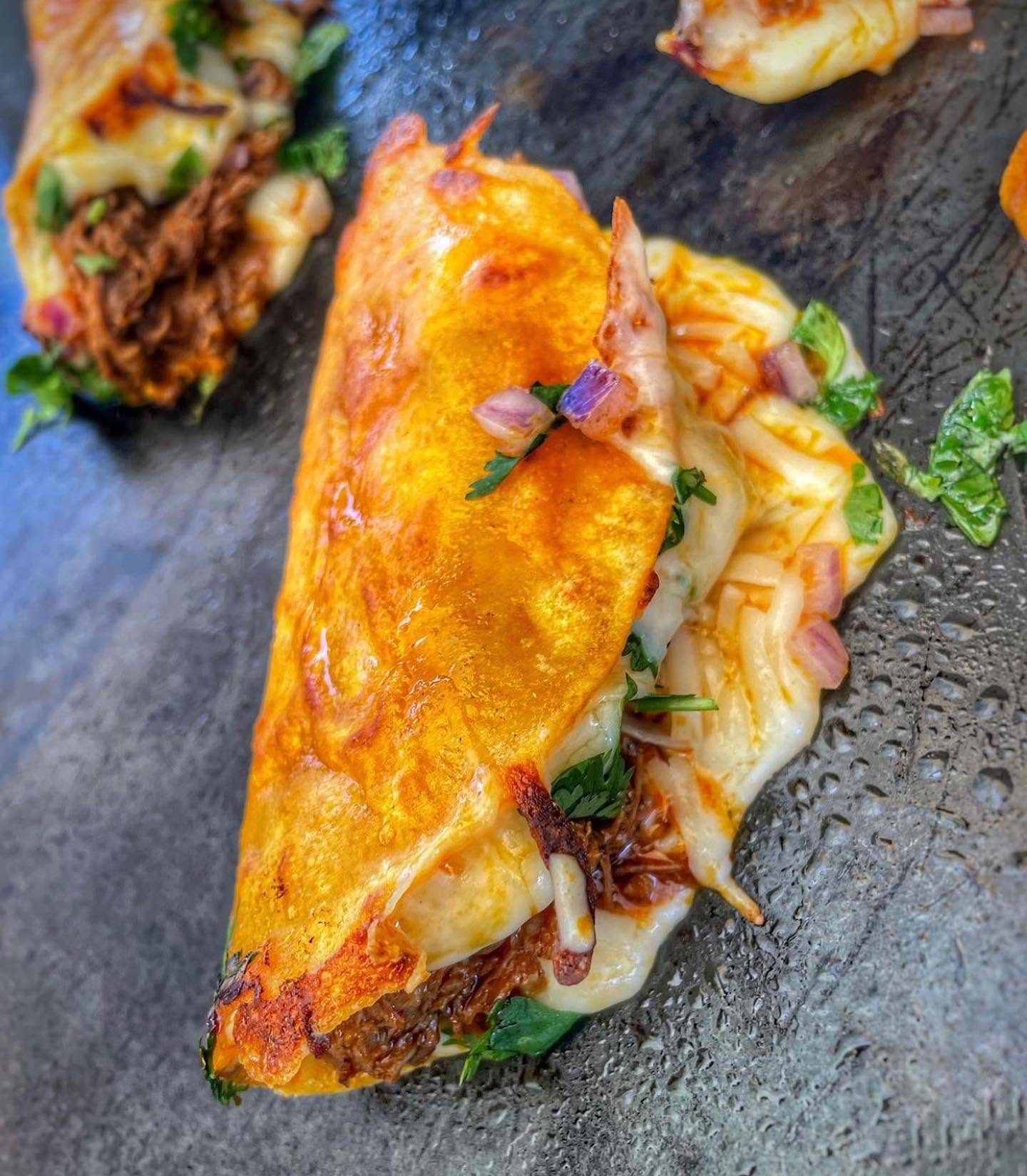 A cheesy quesabirria taco crisping golden on the griddle